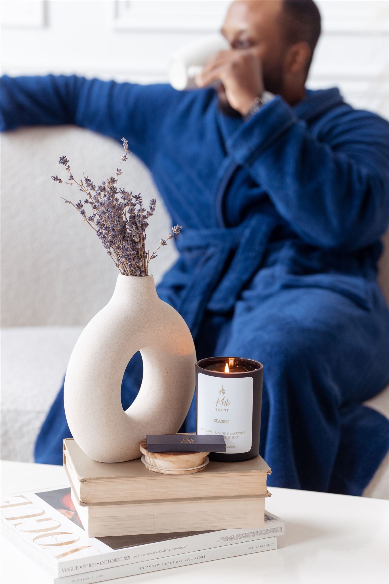 KHB SCENT Eucalyptus, Sage and Lavender vegan candle on a stack of books with a cozy setting