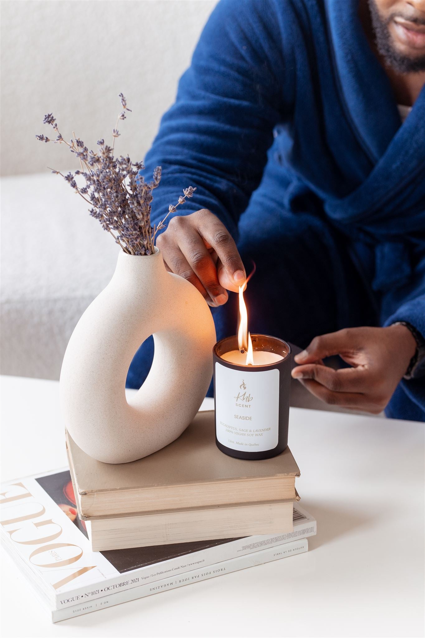 Person lighting a candle using wooden matches for candles beside a decorative vase